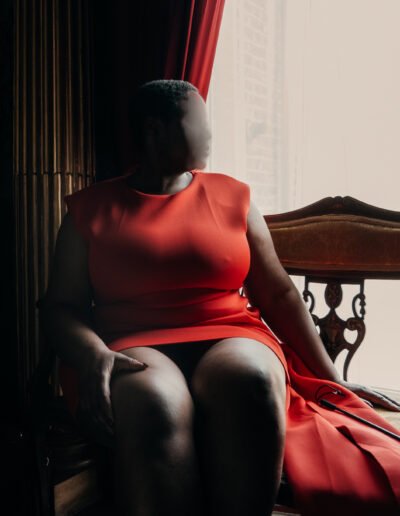 Sable Gold in orange dress on Victorian bench, bare legs crossed, luxury companion Luxembourg